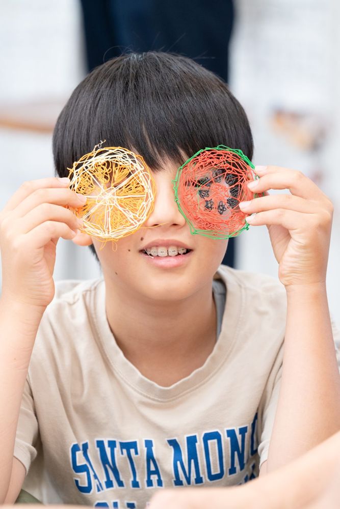 フルーツの作品を目にあてて笑う男の子